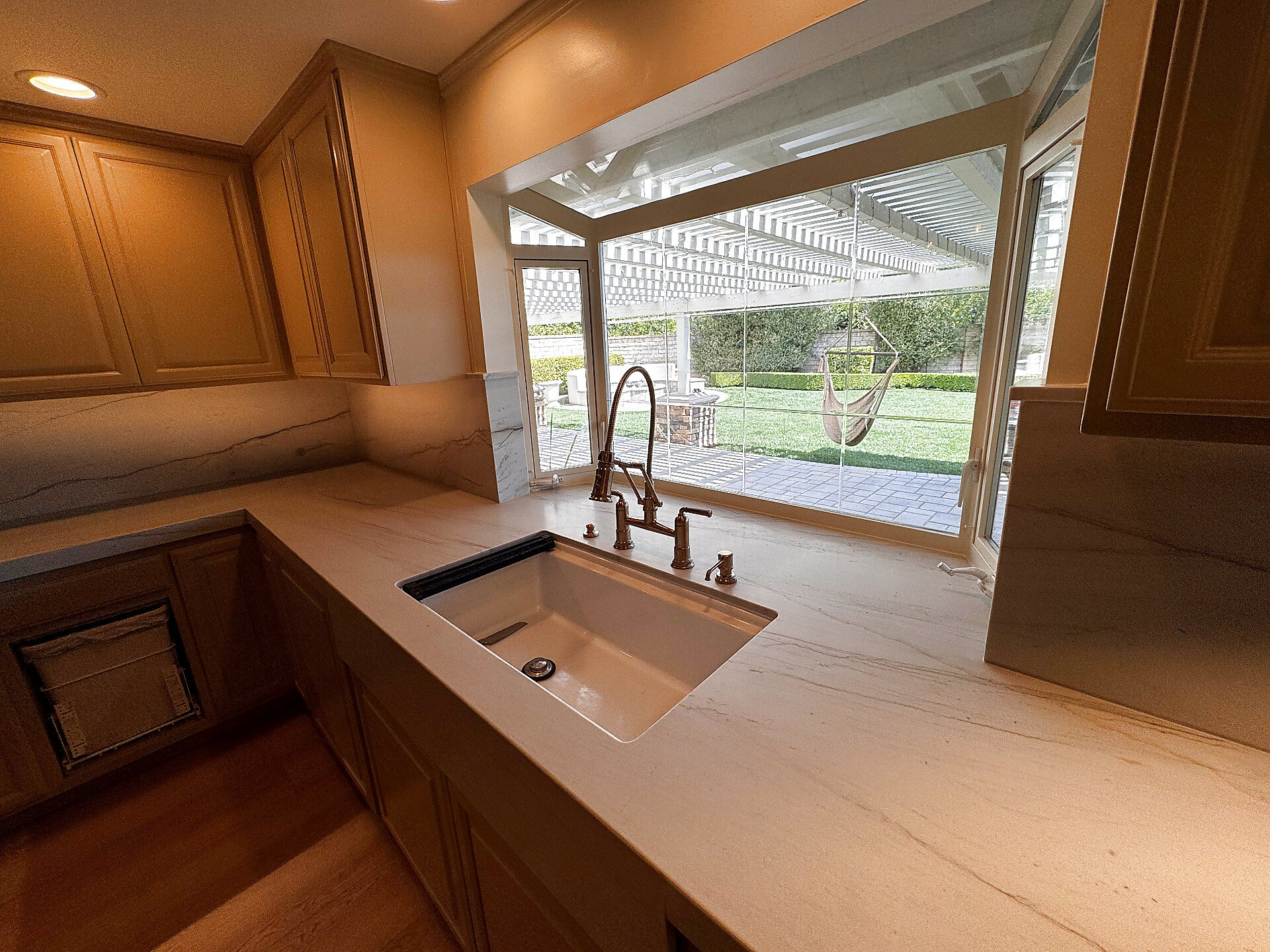 White quartz sink area with integrated apron-front sink and large picture window