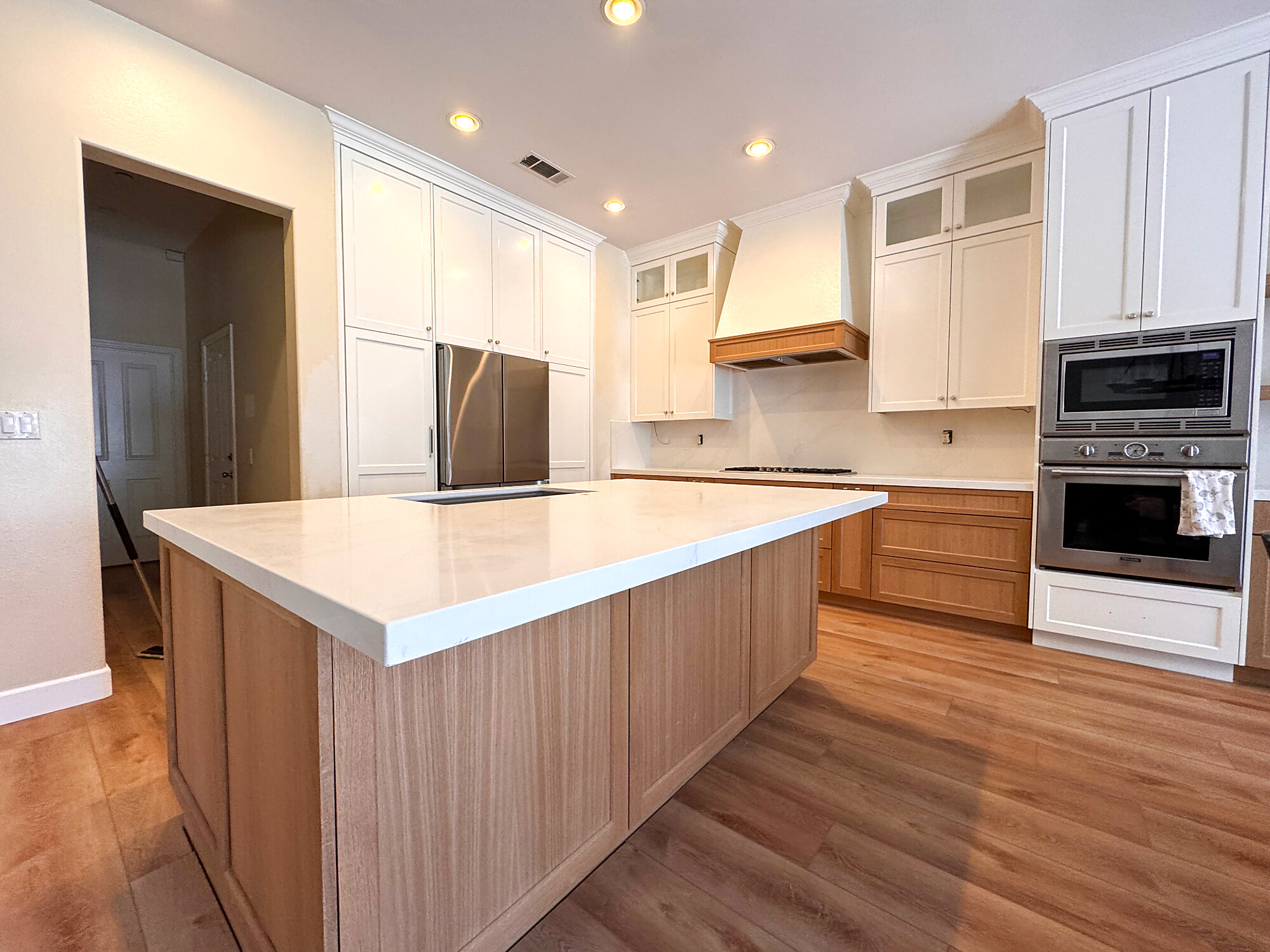 Bright white kitchen with quartz waterfall island and white oak cabinetry