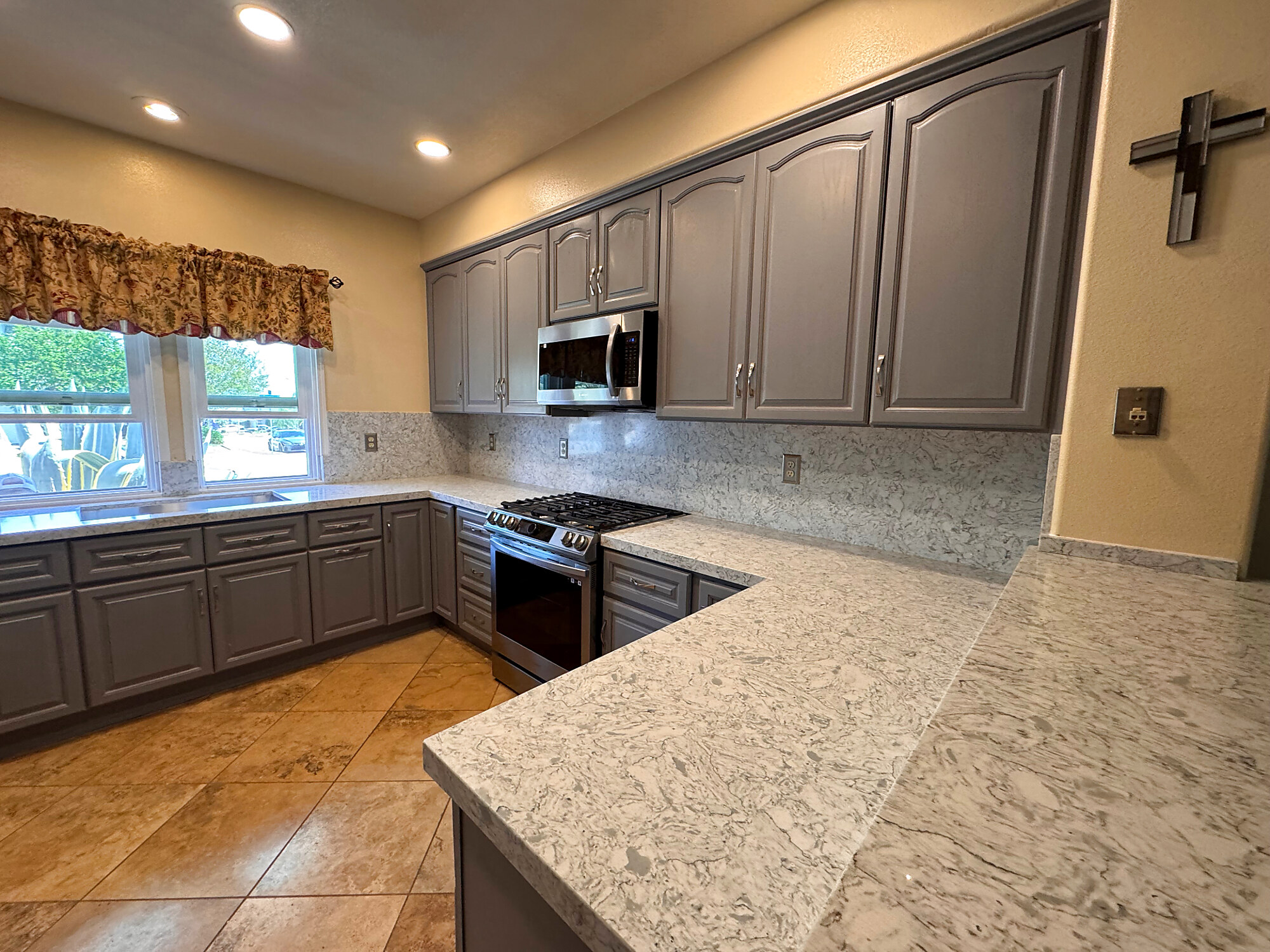 Gray painted cabinets with veined quartz countertops and gas range