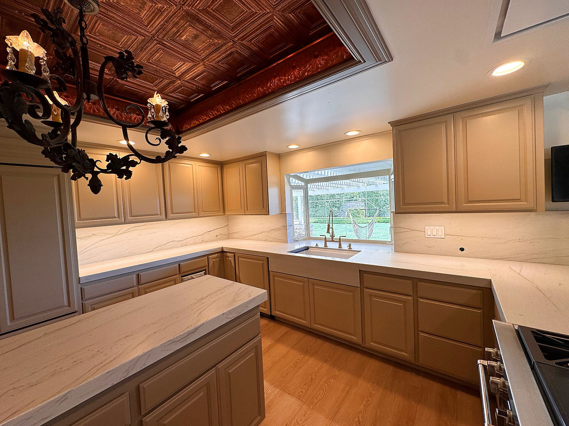 White quartz kitchen with coffered wood ceiling and taupe cabinetry